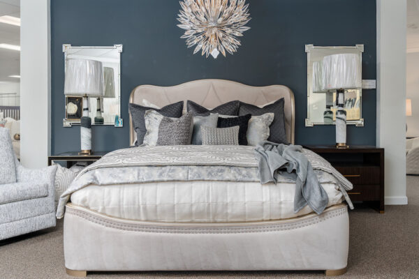 A high-end Caracole bed is accompanied by Uttermost lamps, Ambella nightstands, a Jessica Charles side chair.