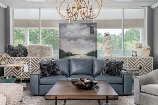 A Hancock & Moore living room sofa is united with Gabby lighting, bar cart, and cabinets and Ambella ottomans.