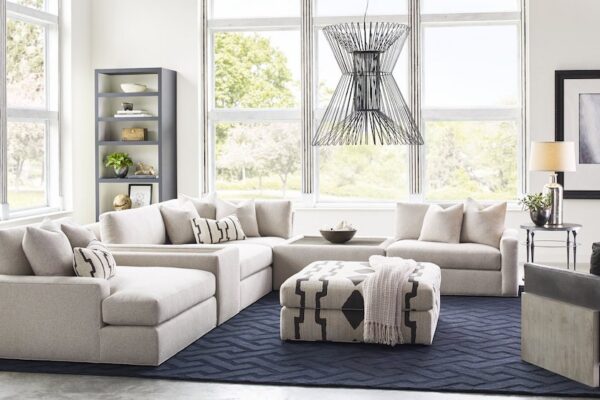 Taylor King living room sectional with throw pillows paired with an ottoman and arm table.