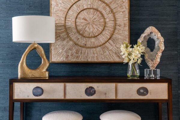 An entryway vignette featuring a John-Richard console table complemented with wall art, a lamp, and other décor.