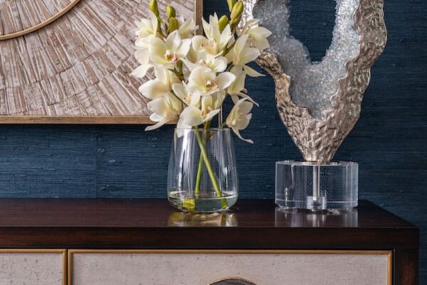 Faux florals and a sculpture adorn a John-Richard console table with blue agate handles on the drawers.