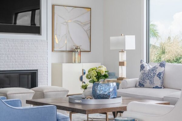A cocktail table, lamps, wall art, and rug complete a transitional style living room design at a Belleair Beach, FL home.